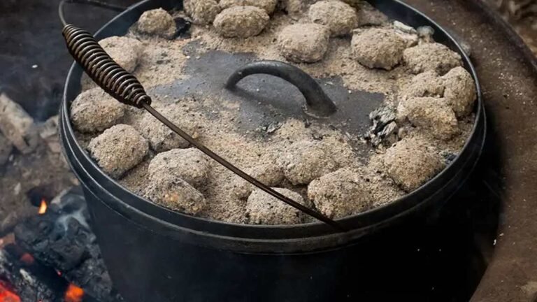 Cast iron camp oven cooking damper on campfire coals