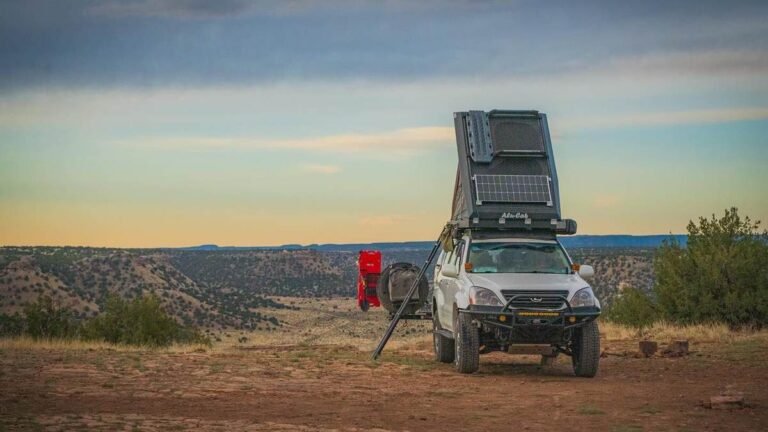 Hard-shell rooftop tent open on a 4WD at an outback campsite